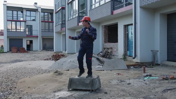 Worker Dances on a Big Stone Near New Buildings