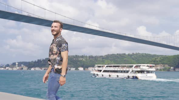 A very happy young man is walking against the view of the Bosphorus.