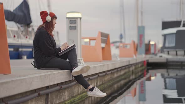 Girl in Hat Work Networks on the Tablet in a Summer Marina on the Sunset