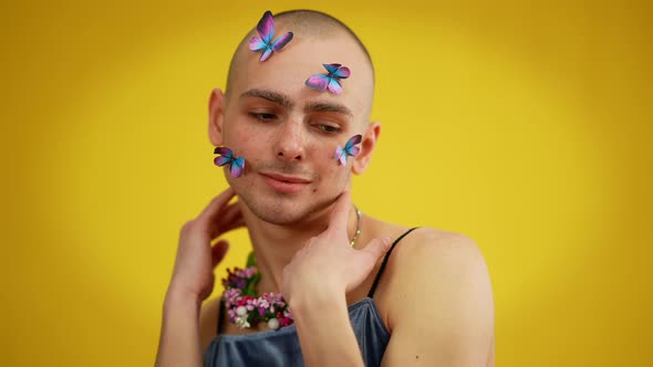 Portrait of Cheerful Male Caucasian Queer with Butterflies on Face in Dress and Floral Necklace