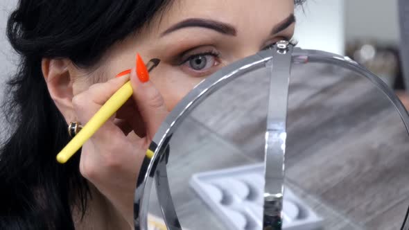 Young Beautiful Showy Woman in Front of the Mirror Applies Face and Eye Makeup with a Special Brush