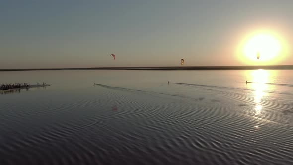 Kite Surfers Are Gliding on Pink Water of the Lake During Sunset, 