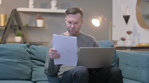 Casual Man with Laptop Having Failure on Documents Sofa