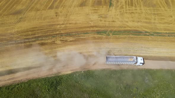 Aerial View of Lorry Cargo Truck Driving on Dirt Road Between Agricultural Wheat Fields