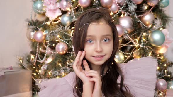 Girl in a Pink Dress Sits at the Christmas Tree and is Photographed By Photographer in the Studio