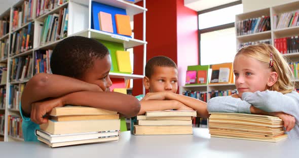 School kids leaning on stack of books in library