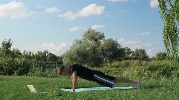 Man doing push-ups on grass in park