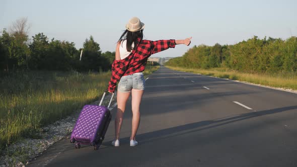 Young Woman with a Suitcase on Road. Funny Beautiful Girl Traveler. Travel Concept Video.