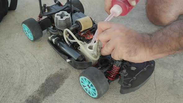 Adding red colored fuel to the remote controlled rc nitro car tank before the race