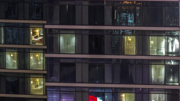 Apartment Windows of a Glazed Skyscraper Glow at Night with City Lights Reflection Aerial Timelapse