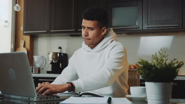 Black Man in White Hoodie Working Home on the Computer