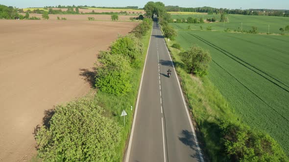 Motorcyclist Rides Between Planted and Yellow Ripe Fields