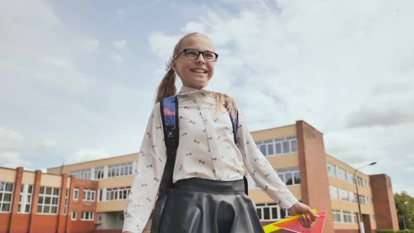 Happy Eleven-year Schoolgirl Runs with a Backpack and Exercise Books After School.