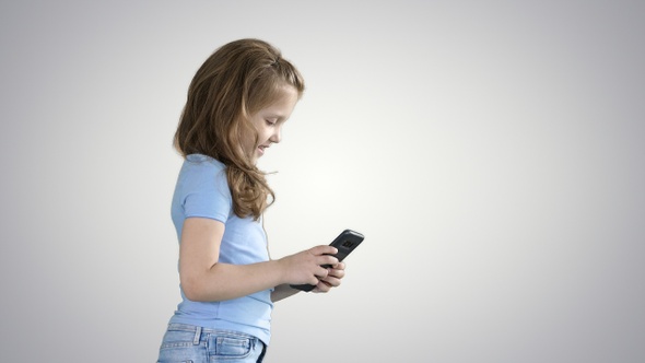 Little girl is playing with smartphone while walking on