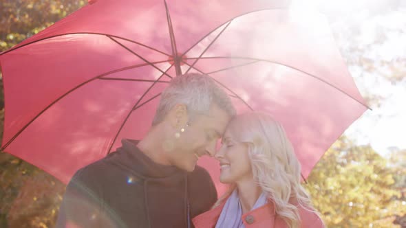 couple touching noses outdoors with umbrella