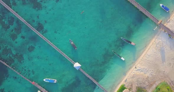 Stunning aerial flight over clear turqoise water at the beach in Mabul, Malaysia