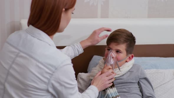 Mom Helps Male Child with Poor Health Breathe Nebulizer During Illness and Treatment at Home