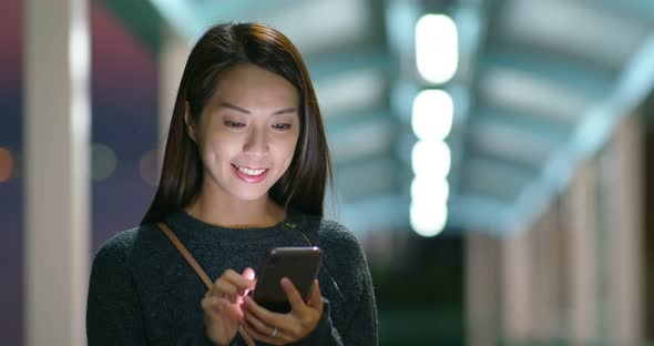 Woman use of mobile phone in city at night