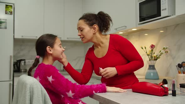 Caring Mother Teaching Daughter Putting on Makeup on Face Skin Indoors