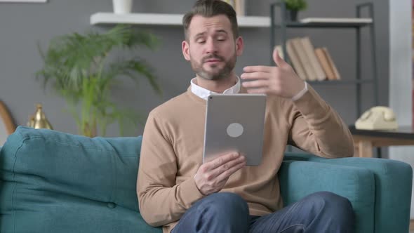 Man Talking on Video Call on Tablet on Sofa