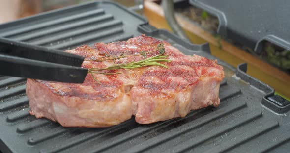 Juicy Beef Steak with Rosemary is Cooked on an Electric Grill