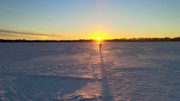 Skier crossing a frozen lake during a beautiful sunset, explore minnesota, protect our winters and k