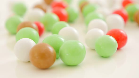 Colorful button-shaped candies on white reflective surface 4K 2160p UltraHD footage - Colorful round