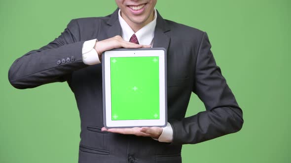 Young Happy Asian Businessman Showing Digital Tablet To Camera