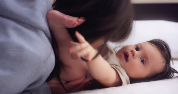 Loving Mother Tickles and Kisses Her Baby Girl