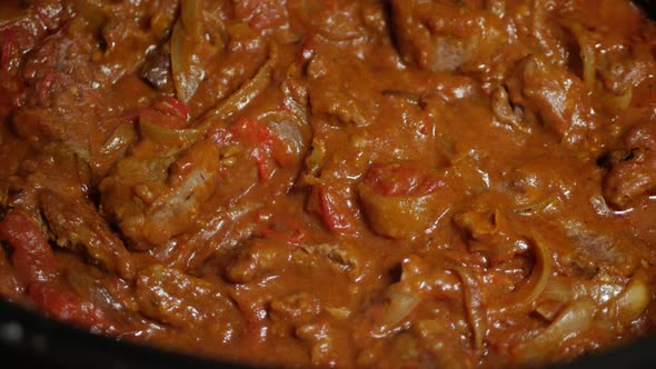 Indian beef curry being slow cooked. CLOSE UP.