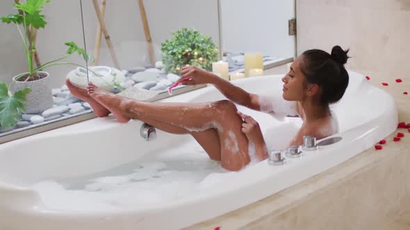 Mixed race woman lying in a bathtub at home
