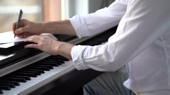 The composer plays the piano composes music and writes it down with notes