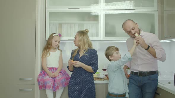 Joyful Parents with Siblings Sharing Fruits in Kitchen