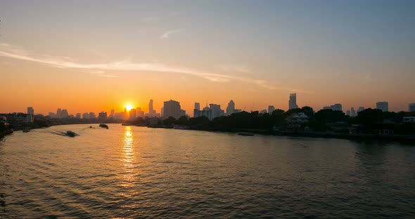 Sunrise beyond Bangkok skyline, Thailand. Boats cruising on the Chao Praya River. Time lapse