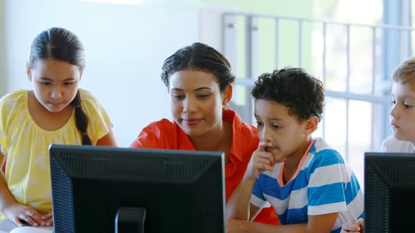 Teacher assisting kids in learning computer