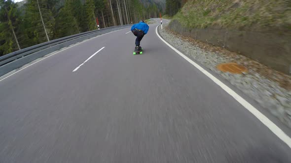 A skateboarder downhill skateboarding on a mountain highway road.