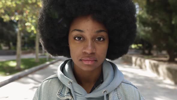 Millennial Hispanic Young Woman with Afro Hair Looking Serious at Camera