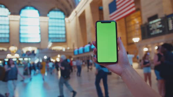 Female hand holding a smartphone with green display