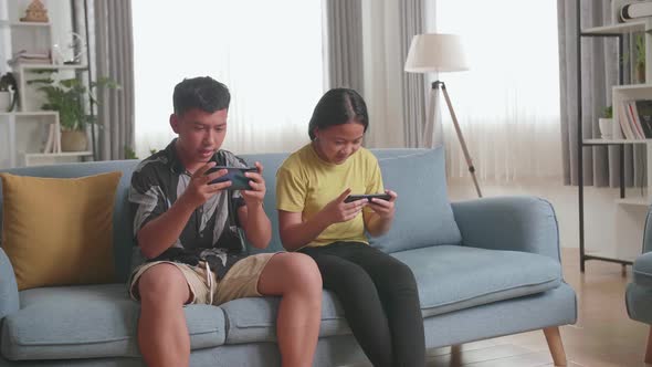 Asian Children Playing Video Games On Mobile Phone At Home