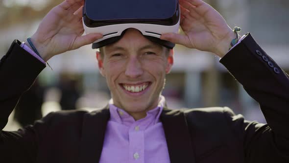 Smiling Young Man Taking Off VR Glasses.