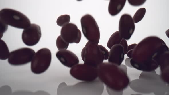 Camera follows dried beans falling on surface. Slow Motion.