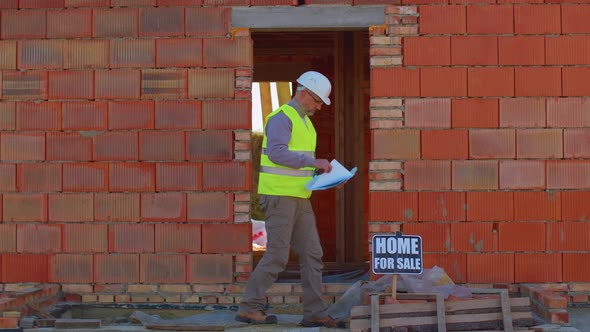 Professional Builder Worker Architect Analyzes Blueprints Dimensions at Construction House Site