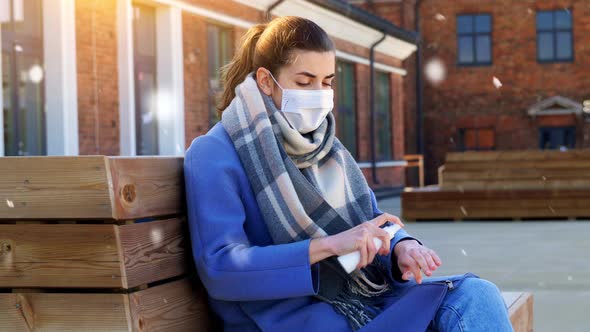 Woman in Mask Using Hand Sanitizer in Winter City