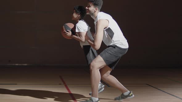 Father Helping Son Shoot Basketball on Indoor Court