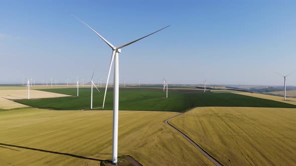 Sliding aerial shot of a faulty wind turbine in the middle of a wind farm on a sunny summer day