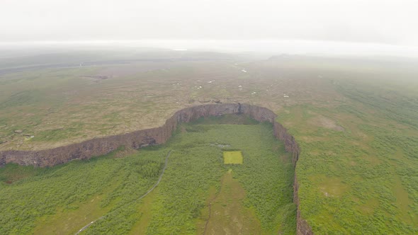 Flying Over Thin Clouds Moving Over Famous Asbyrgi Canyon In Iceland. - aerial