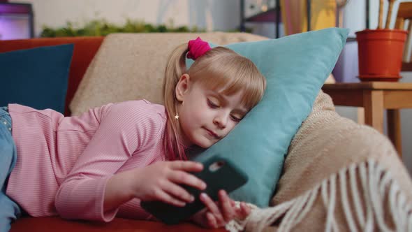 Child Toddler Hold Smartphone Watching Funny Cartoons Chatting with Friends on Couch Alone at Home