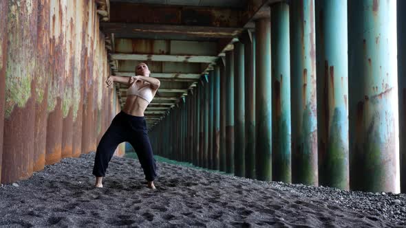 Slender Woman is Dancing Modern Hip Hop Choreography Under Pier of Sea