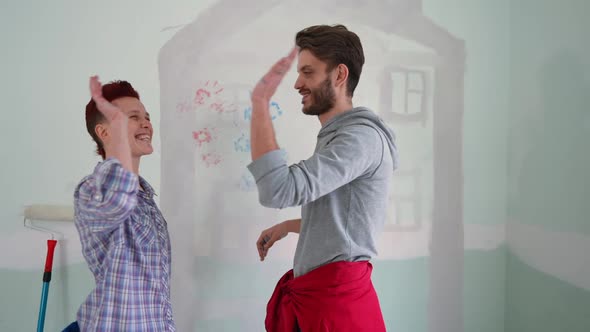 Side View Smiling Couple Gesturing Highfive Laughing Standing in New House Indoors