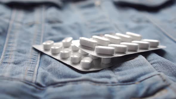 Coronavirus drug. Two packs of white pills fall onto denim. 